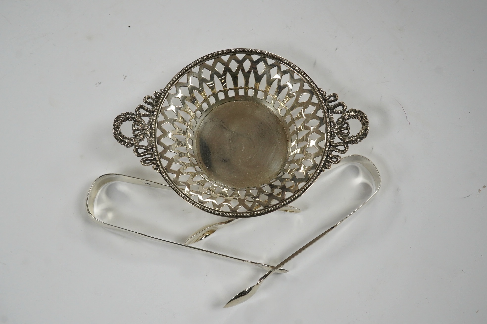 Two pairs of 19th century silver sugar tongs, including London, 1803 and a silver bonbon dish. Condition - fair to good